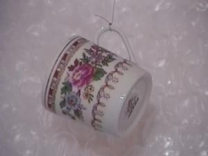 A small, flower-patterned china cup hangs from fishing wire in front of a bubble-wrapped background.
