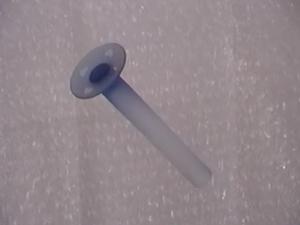 A blue, cylindrical vase hangs upside down from fishing wire in front of a bubble-wrapped background. 